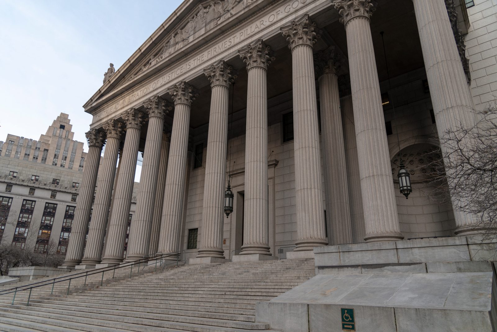 Stone columns and wide granite steps lead up to the entrance of a large neoclassical government building in a city
